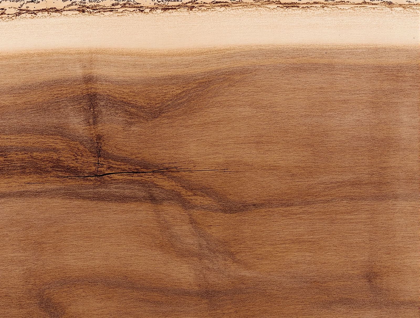 PLACEHOLDER — shot list for the real photographer: a close overhead of a live edge walnut slab surface, oiled, showing grain and the natural bark edge, shot flat under soft north light